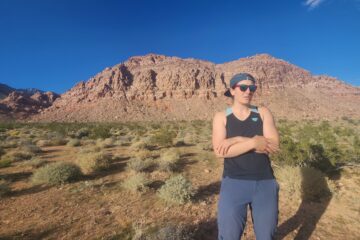 Candid image of Laurel in a tank top with arms crossed. Standing in front of Kraft mountain.